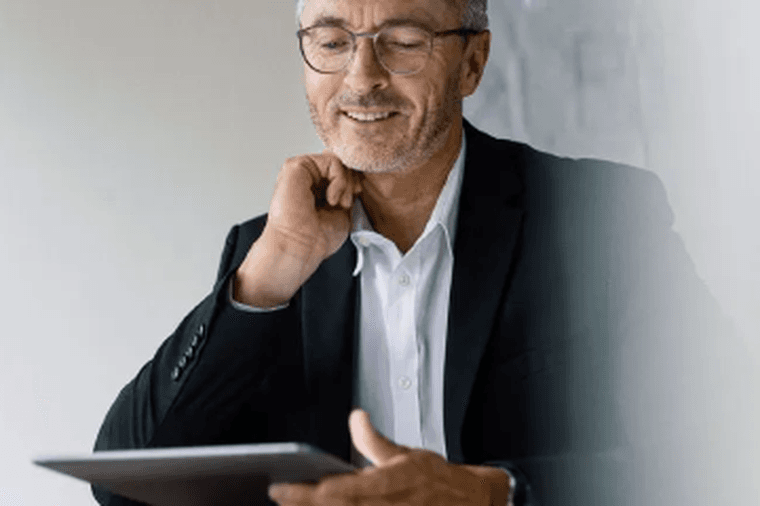 Mann im Anzug mit Brille, der ein Tablet benutzt