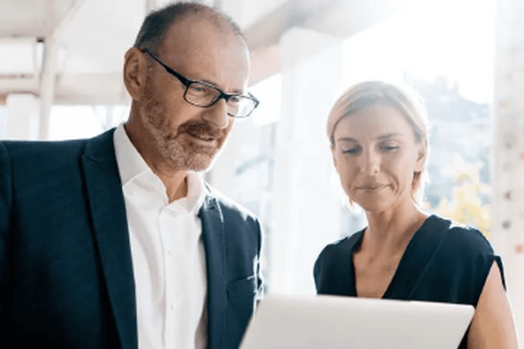 Man showing woman something on a laptop