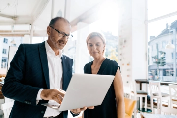 Un homme montre à une femme quelque chose sur un ordinateur portable